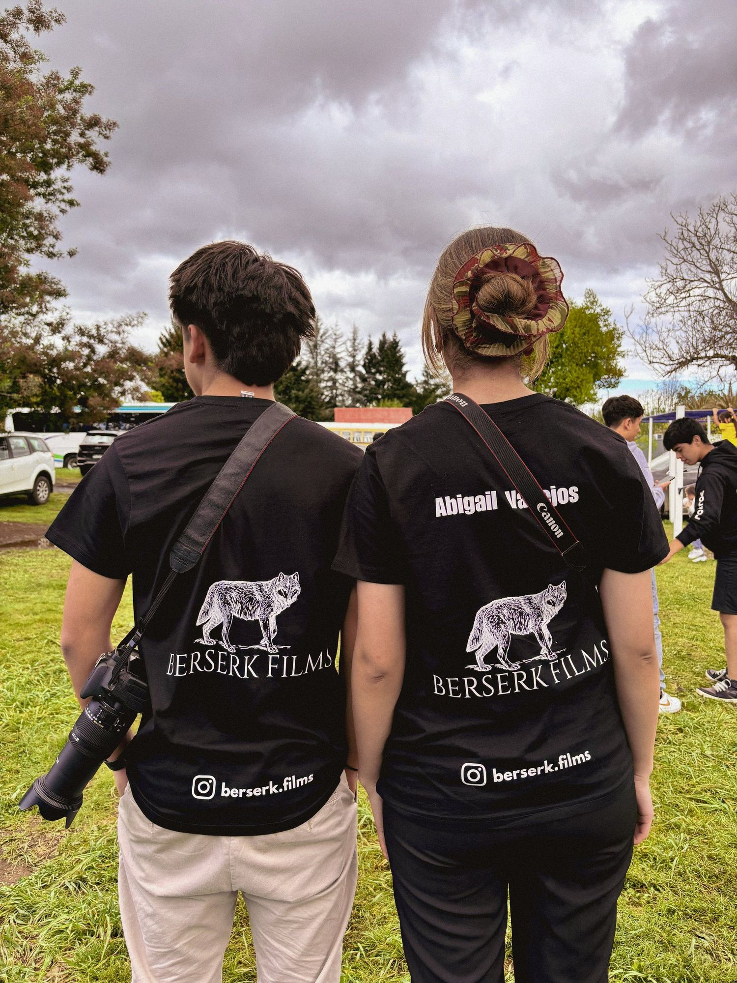 Abigail Vallejos y un integrante del equipo, de espaldas, con poleras de Berserk Films y una cámara