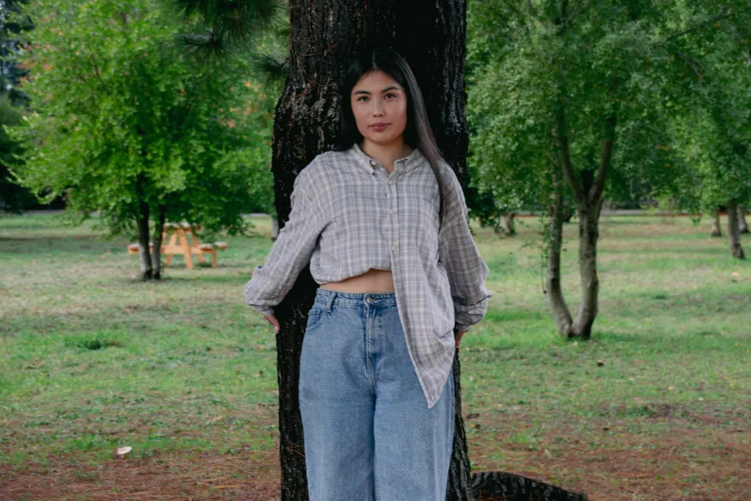 Joven apoyada en un árbol