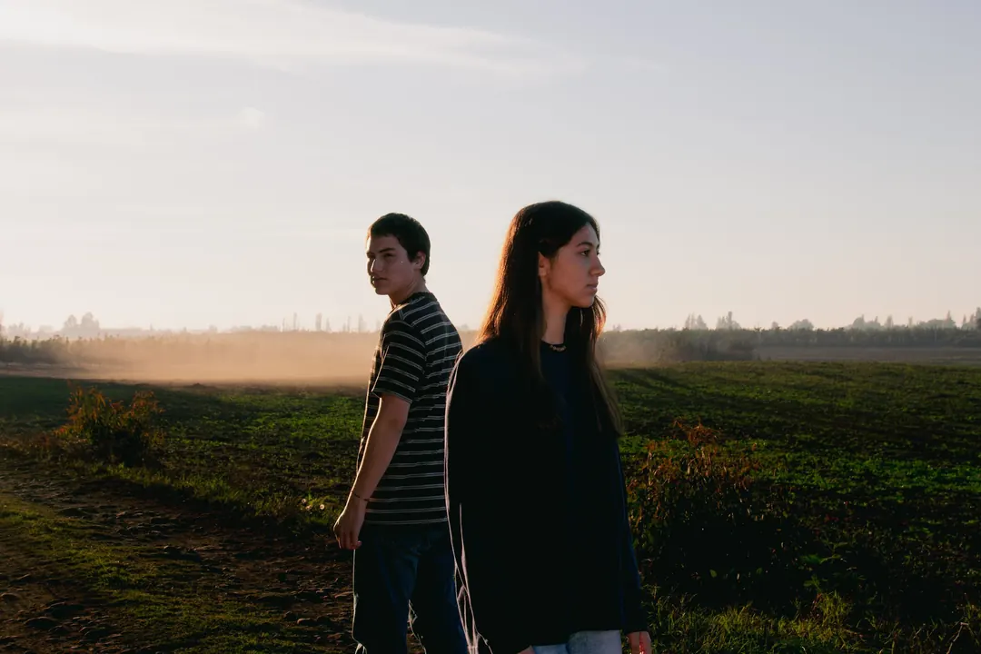 Dos jóvenes de espaldas en un campo al atardecer