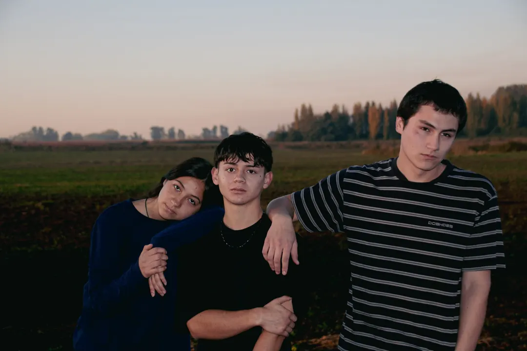 Tres jóvenes abrazados en el campo al atardecer