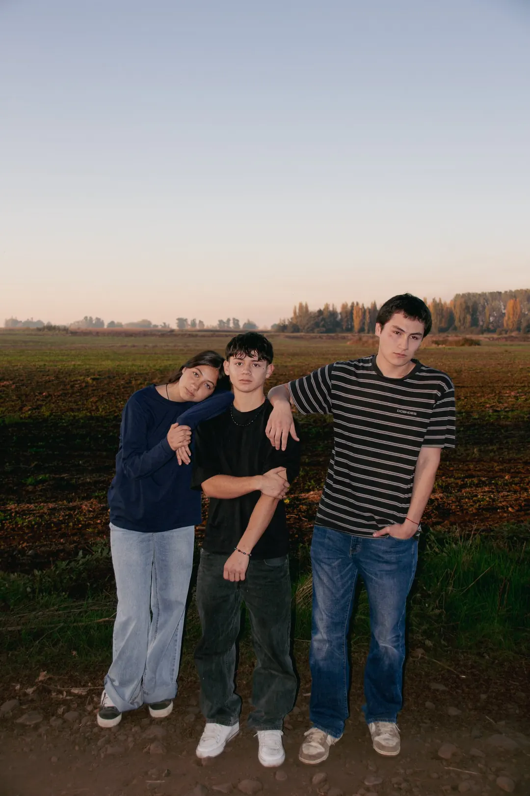 Tres jóvenes de pie en un camino de tierra