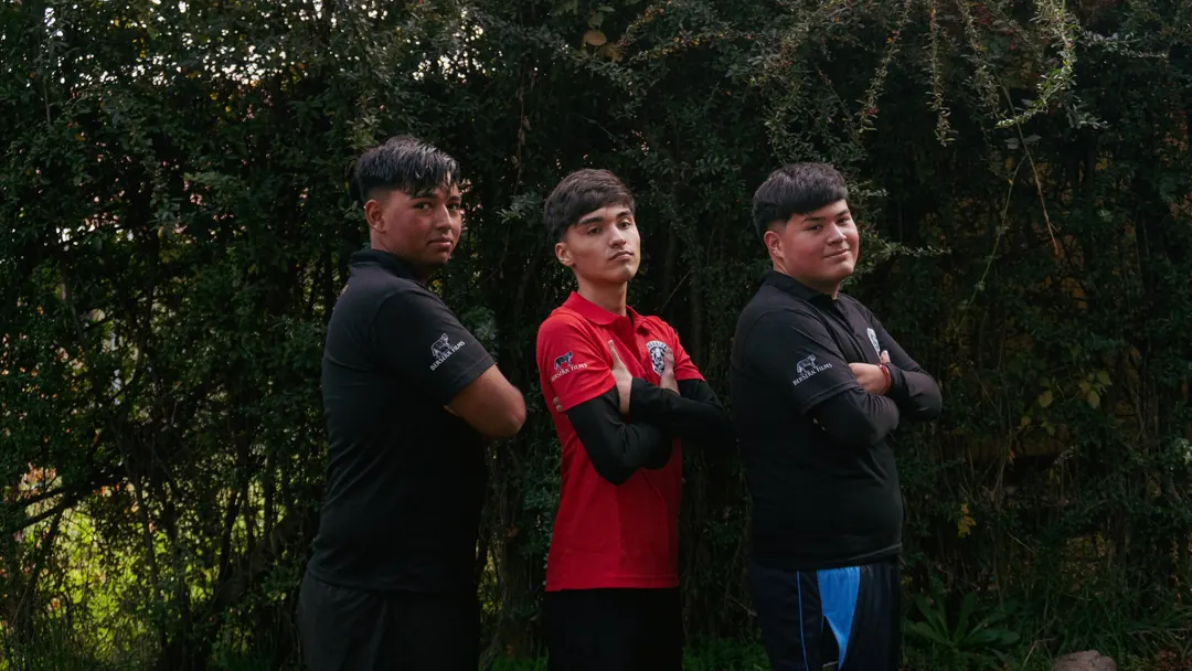 Tres jóvenes frente a un muro de árboles