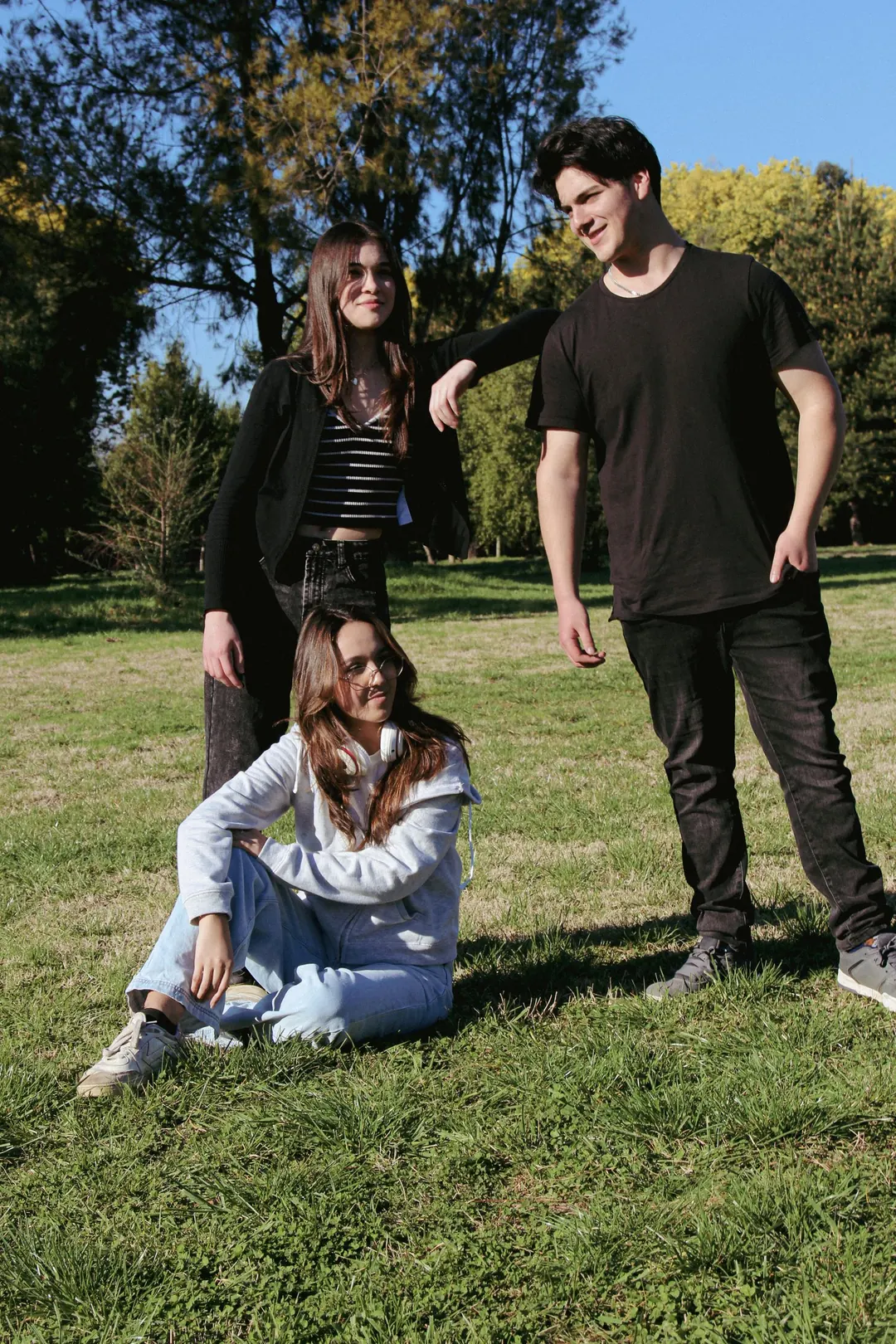 Tres jóvenes en el pasto, a pleno sol