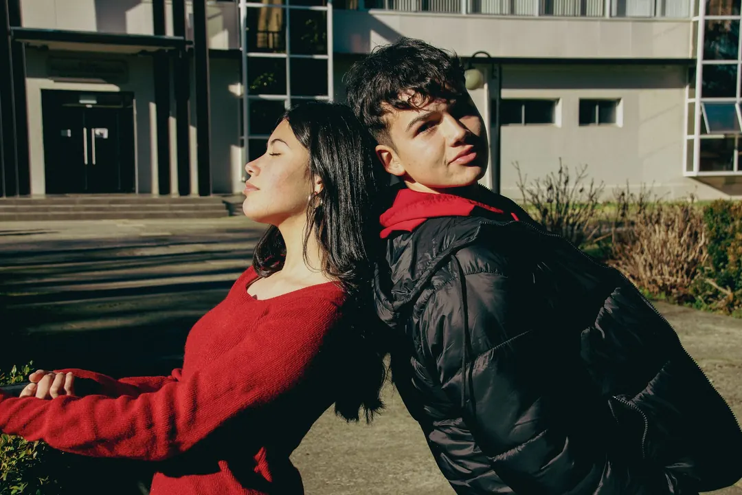 Dos jóvenes espalda con espalda, a pleno sol